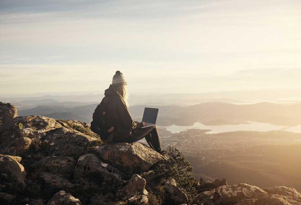 girl-sitting-on-top-of-a-mountain-with-a-laptop